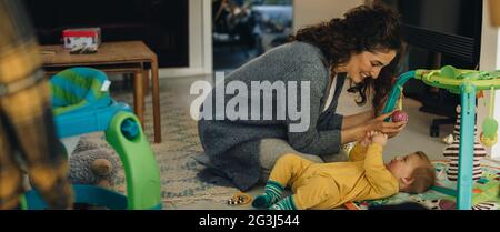 Woman playing with her kid lying on floor at home. Mother and son playing at home. Stock Photo