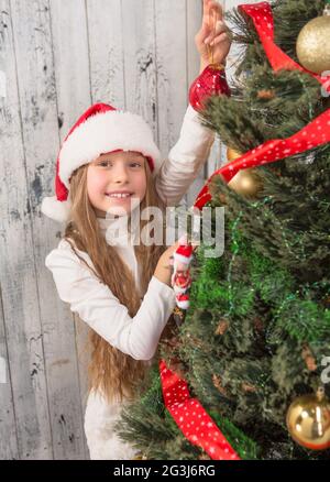 Teenage girl decorating New Year tree at home
