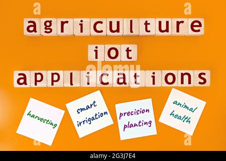 agriculture IoT (internet of things) applications model. wooden cubes with the words "agriculture IoT applications", and sticky notes, on yellow backg Stock Photo