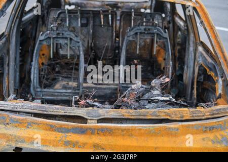 Burnt-out rusty cars on a city street, vandalism. Setting fire to cars by vandals and damage to property Stock Photo