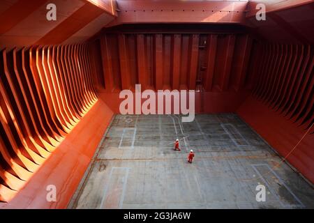 crew preparing cargo hold before loading cement, applying hold block, in the hold of big bulk carrier vessel Stock Photo