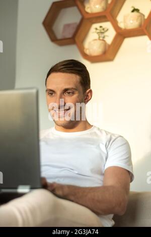young man looking at camera while having a coffee and looking at his cell phone Stock Photo