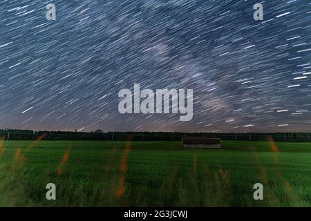 Startrails over a little hut at a farmland at the starry night, beautiful nature and concept for motion of the earth. Stock Photo