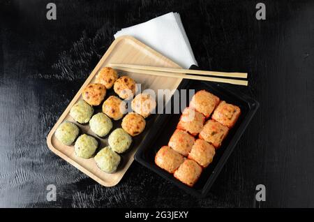 A set of rolls with chopsticks and paper napkins on a black wooden background. Selective focus. Stock Photo