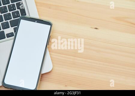 Mobile phone with blank screen on top of computer. Stock Photo
