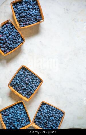 Graphic image of wild blueberries in quart containers on a marble counter top. Maine, New England, USA Stock Photo