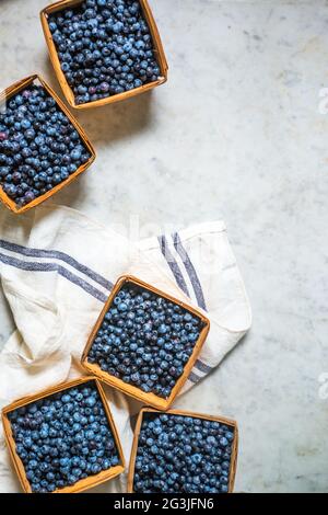 Graphic image of wild blueberries in quart containers on a marble counter top. Maine, New England, USA Stock Photo