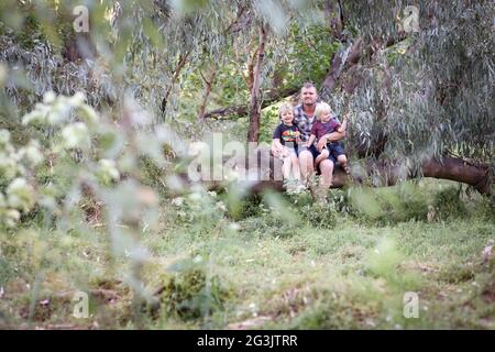 Sons sitting on the knees of their father in the forest Stock Photo