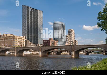 Grand Rapids, MI, USA - June 7, 2008: Grand River with Gillet bridge and Amway Grand Plaza hotel behind under blue sky. 2 tall buildings farther: JW M Stock Photo