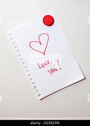 love you note on fridge door hold by red magnet Stock Photo