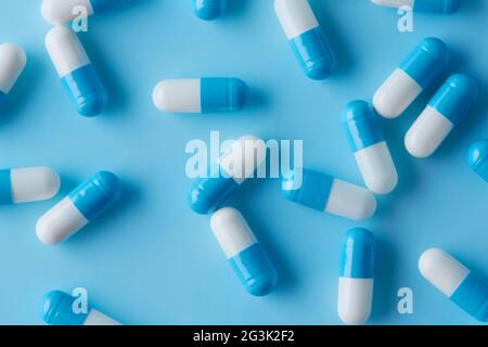 Blue and white capsules pill spread on blue background with shadow . Global healthcare concept. Antibiotics drug resistance. Antimicrobial capsule pil Stock Photo