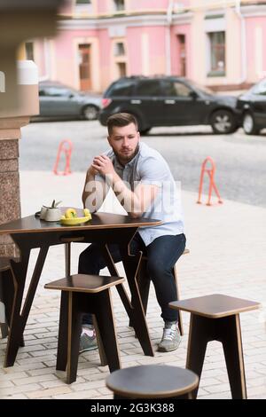 Handsome man sitting in outdoor vegan cafe Stock Photo