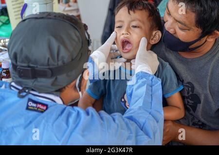 BALI/INDONESIA-MAY 28 2021: An ENT doctor is examining the ears, nose and throat of a pediatric patient. During the COVID-19 pandemic, ENT examination Stock Photo