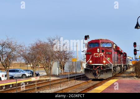 Bensenville, Illinois, USA. Two locomotives lead a Canadian Pacific Railway freight train through commuter station platforms. Stock Photo