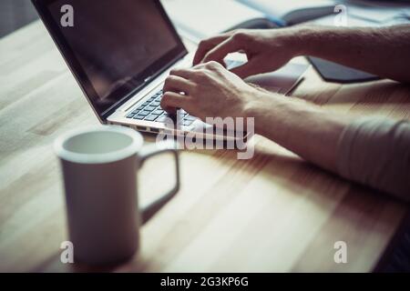 Close up view of mans hands keyboarding on laptop. Stock Photo
