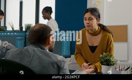 Industrial architect colleagues working and having fun sharing ideas for new mechanical project. Engineers using pc with CAD software and two monitors in start up company innovating motor prototype. Stock Photo