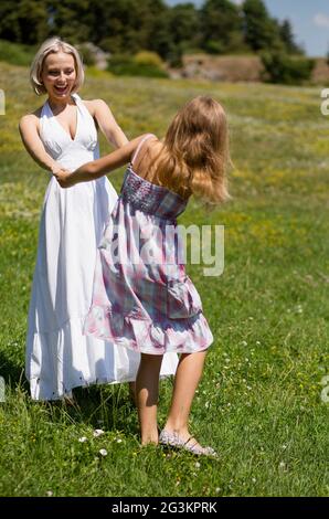 Mom and daughter in field having fun and dancing. Stock Photo