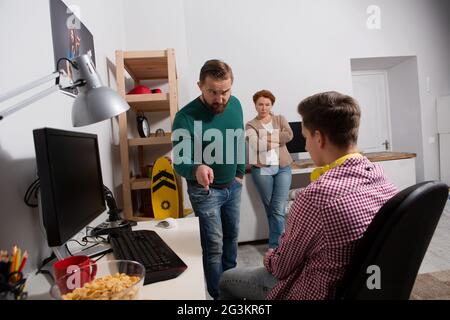 Parents quarreling with teenage son addicted to computer games. Stock Photo