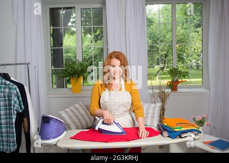Housewife doing laundry and ironing. Stock Photo