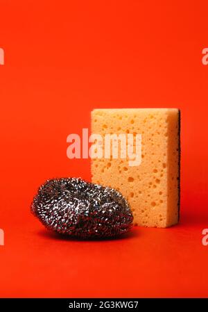 Kitchen cleaning tools, dish washing sponge and metal brush on red background insulation. Stock Photo