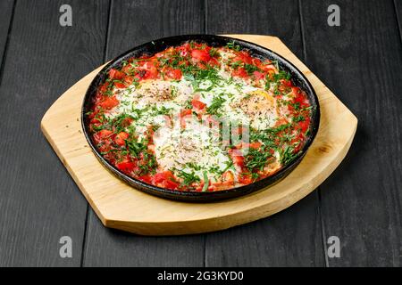 Eggs fried with ham and tomato in cast iron skillet Stock Photo