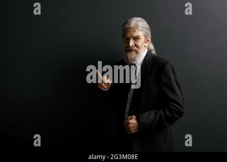 Elrderly stylish man in black jacket holding cigar. Stock Photo