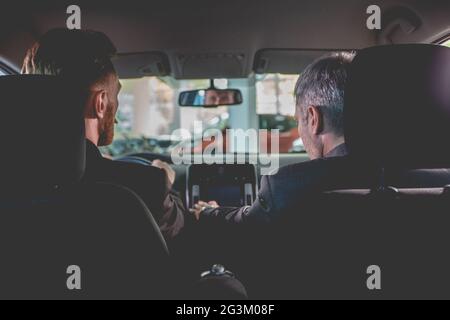 Vehicle dealer and buyer sitting inside a new car in auto showroom. Stock Photo