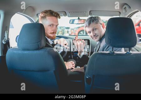 Vehicle dealer and buyer sitting on front seats in new car. Stock Photo