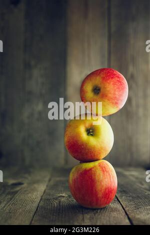 Balance. Three red apples one on another, wooden background Stock Photo
