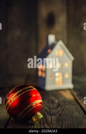 Christmas Bauble and white house shaped ceramics candle holder on rustic wooden background Stock Photo