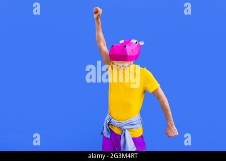 Cool man wearing 3d origami mask with stylish colored clothes - Creative concept for advertising, animal head mask doing funny things on colorful back Stock Photo