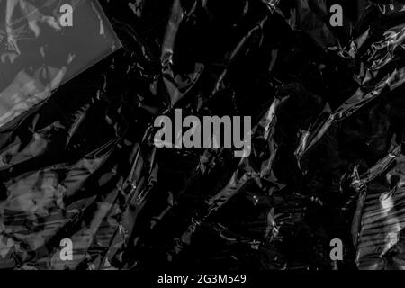 Black crushed wrinkled dark plastic close-up. Abstract dark background. Crumpled plastic wrap Stock Photo