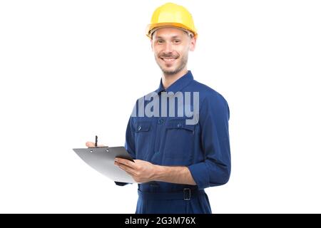 Horizontal medium portrait of successful handsome young adult Caucasian construction engineer wearing uniform holding clipboard with papers Stock Photo