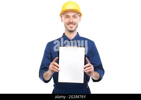 Horizontal medium portrait of successful handsome young adult Caucasian construction engineer wearing uniform holding clipboard with papers Stock Photo