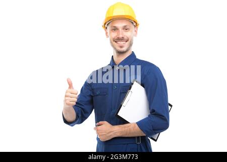 Horizontal medium portrait of successful handsome young adult Caucasian construction engineer wearing uniform holding clipboard with papers Stock Photo