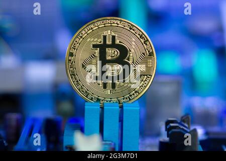 Golden Bitcoin coin on a blurred background of microchips and radio components in blue light. New digital cryptocurrency concept of the blockchain Stock Photo