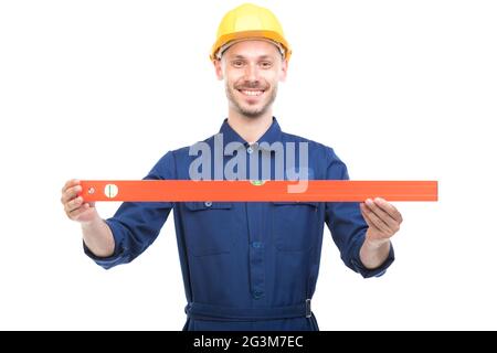 Portrait of successful handsome young adult Caucasian construction engineer wearing uniform with hardhat measuring level of something Stock Photo
