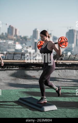 Attractive woman working out, doing lunges with weight. Stock Photo