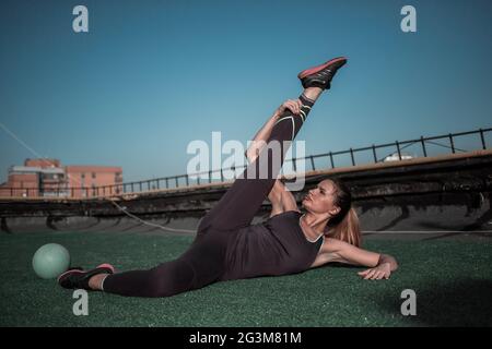 View of young woman stretching legs on the roof. Stock Photo