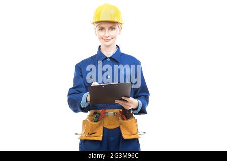 Horizontal medium portrait of modern professional female construction worker wearing blue uniform holding clipboard with papers making notes Stock Photo
