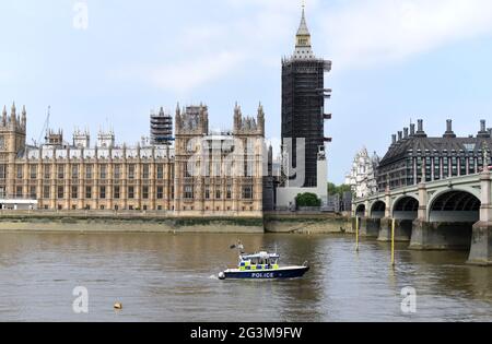 A Police boat passes along the River Thames past the Palace of Westminster on a warm and bright June day Stock Photo