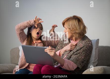 Little cute girl and her grandmother looking at photos on tablet Stock Photo