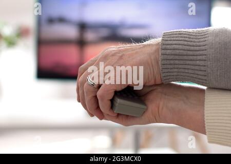 Two hands holding TV remote. Stock Photo