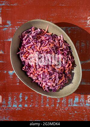 Bowl of freshly made coleslaw on a brown and blue rustic background, shot from above. Stock Photo