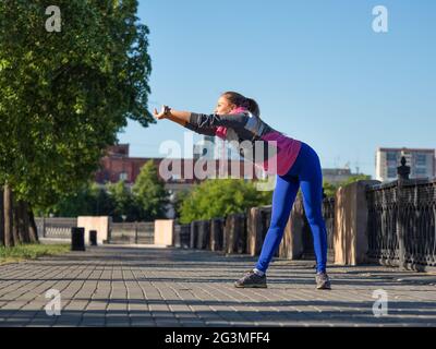 Woman is warming up. She stretches her back muscles before your morning run. Stock Photo