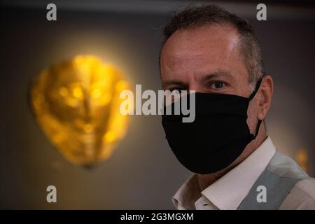 (210617) -- ATHENS, June 17, 2021 (Xinhua) -- Dr. Constantinos Paschalidis, Curator of Antiquities at the National Archaeological Museum, poses in front of the gold death-mask of Agamemnon, in Athens, Greece, June 7, 2021. The imposing golden mask of Agamemnon welcomes visitors at the National Archaeological Museum here, standing out among other finds from the royal cemetery of the ancient city of Mycenae on the Peloponnese peninsula dating back to the 16th century BC. TO GO WITH 'Interview: Ancient Greek golden death-masks of Mycenae still engulfed in mystery, says archaeologist' (Xinhua/Ma Stock Photo