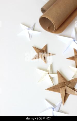 Creative Design Mockup with Kraft Paper Rolls and Origami Stars. Minimal Christmas Background with Copy Space. Stock Photo