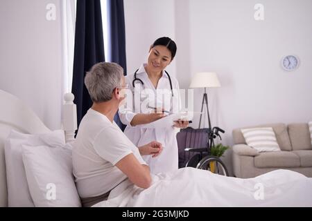 Nurse checking up on patient in bed. Stock Photo