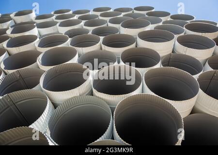 Downpipe warehouse. Steel pipes, parts for the construction of a roof drainage system in a warehouse. Stack of stainless steel pipes. Stock Photo