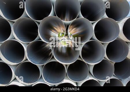 Downpipe warehouse. Steel pipes, parts for the construction of a roof drainage system in a warehouse. Stack of stainless steel pipes. Stock Photo